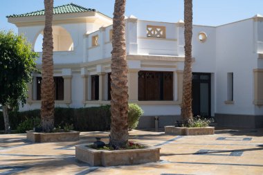 Palmiye ağaçları kumsalda beyaz eve karşı mavi gökyüzü ve kumla
