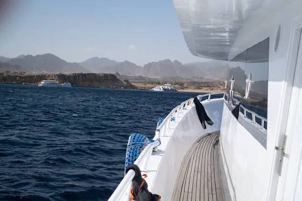 Beautiful white private motor yacht for a boat trip on the Red Sea, Panoramic view of the Red Sea, coral reef and moored pleasure boats. Blue and white seascape, white boats and clear blue water with cloudy blue sky, snorkeling boats