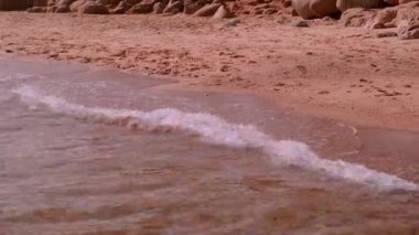 slow motion of foamy waves rolling towards white sand beach under low sunlight