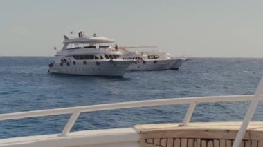 Mısır, Sharm El Sheikh - 8 Şubat 2023: Güneşli bir günde mavi denizde büyük beyaz bir yat, yat limanından ayrılan lüks bir yatın yan görüntüsü. Mısır Kızıl Deniz 'de Gemi Gezisi.