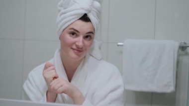 Kız ellerini krem sürmüş ve masaj yapmış, beyaz bir bornoz, banyo, el bakımı, nemlendirici cilt kremi, yakın çekim