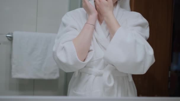 白いバスローブ バスルーム 手のスキンケア 保湿スキンクリーム クローズアップを身に着けている 彼女はクリームとマッサージで彼女の手をスミア — ストック動画