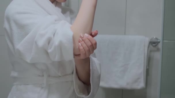 女孩在手上涂上奶油并按摩 还穿着白色浴衣 手部护肤 润肤霜 — 图库视频影像