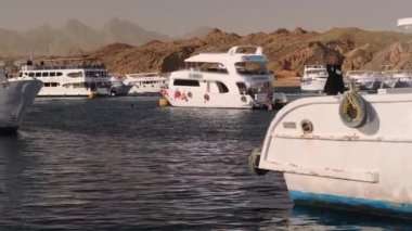Güneşli bir günde mavi denizde yelken açan büyük beyaz bir yat. Geminin rıhtımından ayrılan lüks bir yatın yan görüntüsü. Kızıl Deniz 'de Mısır Gemisi. Bir yatta tatil.