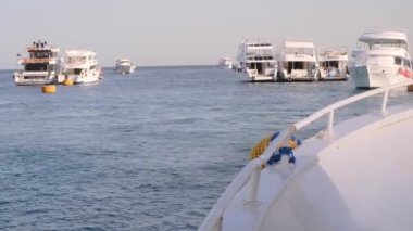 Güneşli bir günde mavi denizde yelken açan büyük beyaz bir yat. Geminin rıhtımından ayrılan lüks bir yatın yan görüntüsü. Kızıl Deniz 'de Mısır Gemisi. Bir yatta tatil.