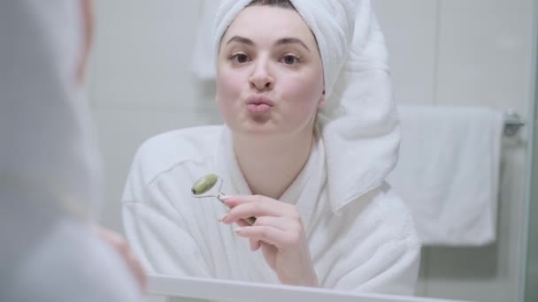Lány Arcmasszázst Csinál Egy Jáde Görgővel Fürdőszobában Van Fehér Fürdőköpenybe — Stock videók