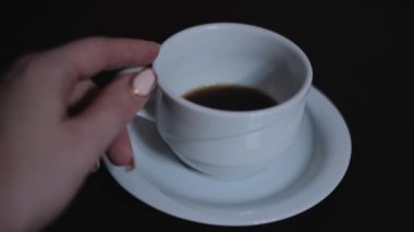 Kadın eli, beyaz bir fincan sıcak kahveyi ağır çekimde alır. Sıcak kahve içeceği konsepti.