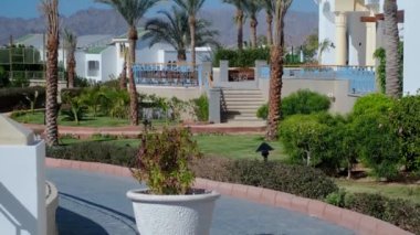 Dağların muhteşem manzaralı bir otel, beyaz mimari, palmiye ağaçları. Lüks, güneşli bir otel. Deniz kenarında harika bir tatil