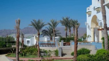 Güneşli bir günde palmiye ağaçları olan doğulu meçhul evler, zaman aşımı, Mısır 'da bir otel binasının güzel beyaz mimarisi.