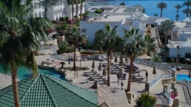 Şatafatlı mavi havuzu, palmiye ağaçları, su kaydırakları, kumsal şemsiyeleri ve Mısır 'da güneş pansiyonları olan güneşli bir otel. Lüks, güneşli bir otel. Sharm 'da kalmak harikaydı.