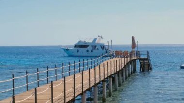 Suda ahşap duba, boş duba, denizde demirli gemi, güneş suya yansıyor, yaz günü, tahta iskele denize dökülüyor.