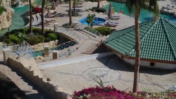 エジプトの豪華な青いプール ヤシの木 ウォータースライド ビーチパラソル サンラウンジャー付きのサニーホテルリゾート 豪華な日当たりの良いホテル Sharm宿泊の場所 — ストック動画