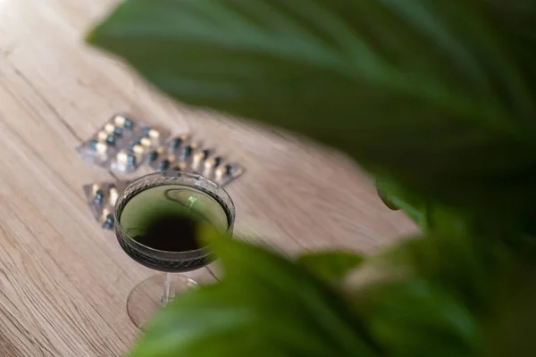 クロロフィル抽出物は 緑色の葉を持つ木製の背景にガラス中のきれいな水に注ぎ込まれます 水のガラス中の液体クロロフィル スーパーフード 健康的な食事 デトックスと食事の概念 — ストック写真