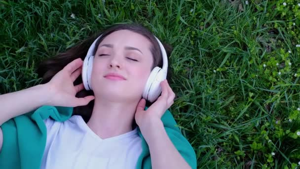 Ontspannen Vrouw Liggend Het Gras Luisteren Naar Muziek Met Koptelefoon — Stockvideo