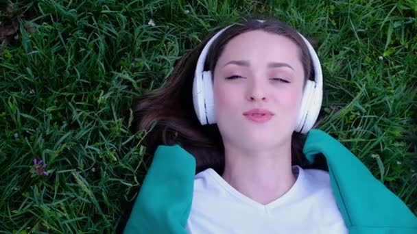 Ontspannen Vrouw Liggend Het Gras Luisteren Naar Muziek Met Koptelefoon — Stockvideo