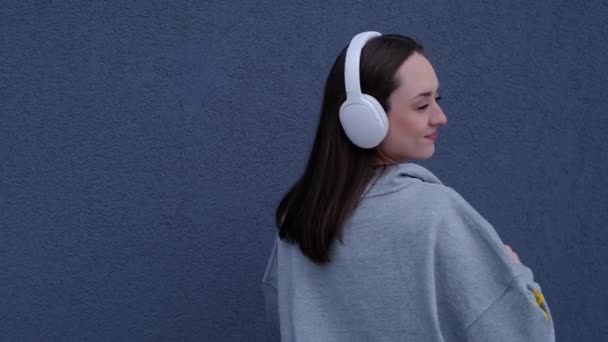 全身上下的白人女孩穿着耳机听音乐 在灰色背景下跳舞 — 图库视频影像