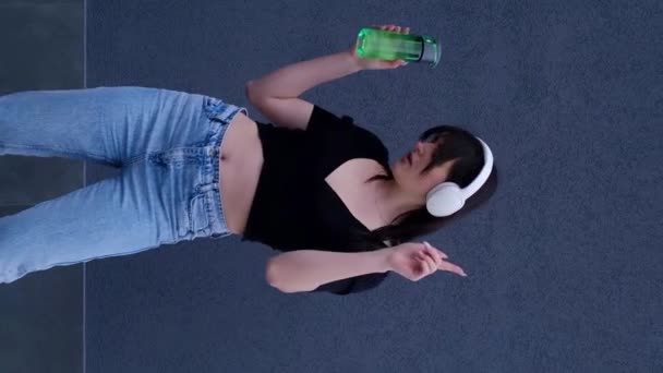Chica Auriculares Bailando Sobre Fondo Gris Con Una Botella Agua — Vídeos de Stock