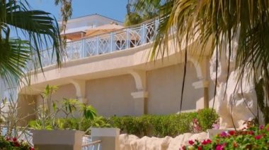 Beyazlı otel. Bahçe manzarası, havuz ve tropik palmiye ağaçları