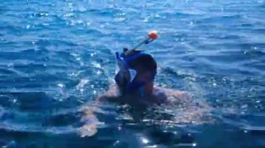 Maskeli bir adam denizde yüzüyor. Tropikal bir balık sürüsüyle dalış yapan bir erkeğin nefes kesici manzarası. Kafkasyalı kaygısız bir yaz tatilinde egzotik balıklarla dalıyor.