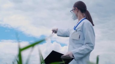 Gözlüklü ve maskeli yetenekli kadın tarım uzmanı organik bir çiftlikteki dijital tablete notlar alıyor. Bir kadın, hidroponik alandaki sebzelerin büyüme kalitesini ve kimyasal verilerini kontrol eder..