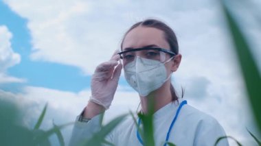 Gözlüklü beyaz bir kadının portresi ve kameraya gülümseyen beyaz bir üniforma, bir çiftlikte duruyor. Laboratuvar asistanı organik yeşilliklerin faydalarından emin..