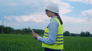 Tabletli bir kasketin içindeki elektrik mühendisi. İş teknolojisi endüstrisi. Elektrik voltajı kulesi konsepti. Dağıtım kabloları olan yüksek voltajlı bir alt istasyon. enerji