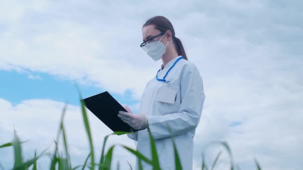 一位戴着护目镜和面罩的熟练女农艺师在一家有机农场的数字平板电脑上做笔记 一名妇女在一个水栽场检查蔬菜的生长质量和化学数据 — 图库视频影像