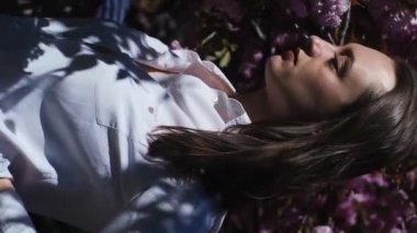 Sakura Ağacı Doğa Üzerine Çiçek Açan Kadın, beyaz gömlekli beyaz saçlı güzel beyaz saçlı kadın, Sakura ağacının yanında pembe çiçekli poz veriyor. Kadınlık ve doğal güzellik kavramı.