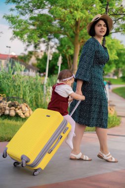 Seyahat konsepti: bavullu anne ve kız bir yolculuğa hazırlanıyor, bir çocuk bavula biniyor, bir anne bir çocuğu bavula sarıyor, denizde tatil yapıyor, ailesiyle seyahat ediyor.