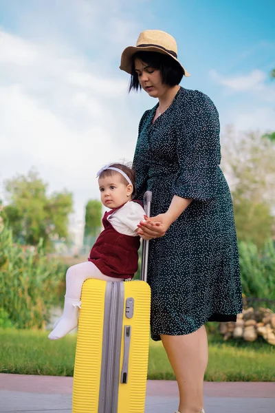 Seyahat konsepti: bavullu anne ve kız bir yolculuğa hazırlanıyor, bir çocuk bavula biniyor, bir anne bir çocuğu bavula sarıyor, denizde tatil yapıyor, ailesiyle seyahat ediyor.