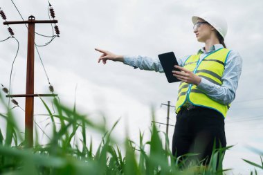 Elektrik mühendisi kadın yüksek voltaj güç endüstrisi, çalışan elektrik işçisi, enerji konsepti, yüksek voltaj elektrik kulesi, elektrik hattı, çalışma tableti