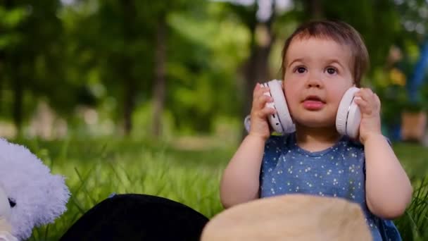 Malé Dítě Žvýkající Poslouchá Hudbu Sluchátkách Tancích Parku Sedí Otevřeném — Stock video