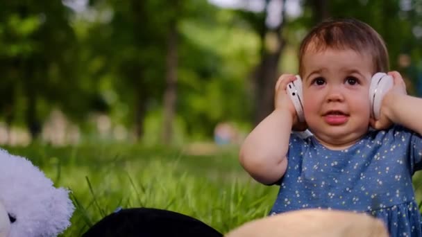 Niño Pequeño Masticando Escucha Música Auriculares Bailes Parque Sienta Una — Vídeos de Stock