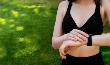 Akıllı saat, kulaklıklar ve parkta koşan sonuçları, antrenman ilerleyişini ve hedefleri olan fitness kadını. Açık hava eğitimi için akıllı saati ve müzik ekipmanı olan genç koşucu ya da sporcu kız