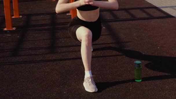 운동복에 소녀는 운동을 아침에 뻗습니다 건강한 생활양식 옥외를 합니다 스쿼트를 — 비디오