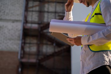 İnşaat mühendisi tablet kullanıyor, bir proje planlıyor, modern bir yapı inşa ediyor, bir plan okuyor. İnşaat alanında çalışan mimar veya mühendis.