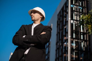 İnşaat alanındaki erkek ustabaşı çalışma kalitesine bakıyor, mimari tasarım bir inşaat alanında dizüstü bilgisayar tutuyor, planları kontrol ediyor. Başarılı mühendis ya da mimar, neşeli iş adamı.