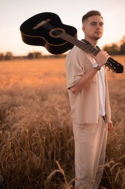 Kampta gitarlı bir adam. Ateşin yanında şarkılar. Kırsaldaki akustik gitarist, müzikal şarkı. Gömlekli, gitarlı seksi bir adam. Hippi modası.