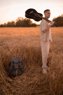 Kampta gitarlı bir adam. Ateşin yanında şarkılar. Kırsaldaki akustik gitarist, müzikal şarkı. Gömlekli, gitarlı seksi bir adam. Hippi modası.