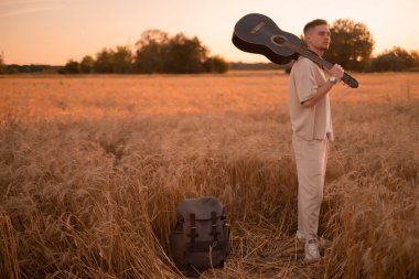 Kampta gitarlı bir adam. Ateşin yanında şarkılar. Kırsaldaki akustik gitarist, müzikal şarkı. Gömlekli, gitarlı seksi bir adam. Hippi modası.