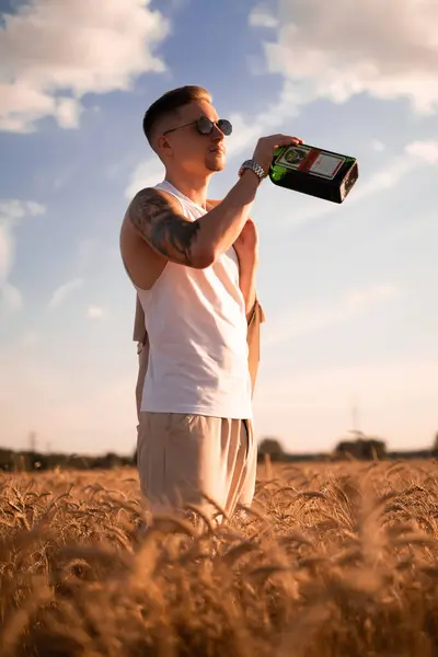 Delicious alcoholic drink in a man\'s hand. A farmer brewer carries fresh cold beer through a field of ripe wheat. Ecological drink, herbal infusion, man drinks