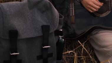 Erkek hipster buğday tarlasında elektro gitarla oynuyor. Uzun saçlı hippi adam arpa otlağında müzik aleti çalıyor. Genç adam doğada dinleniyor. Arka planda güzel bir gün batımı. Yavaş çekim