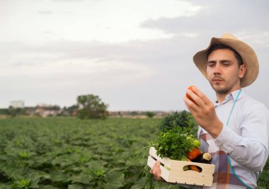 Mutlu genç bir çiftçi taze sebze bir sepeti tutan portresi. Arka plan doğa biyolojik, biyolojik ürünler, biyo ekoloji, kendi elleriyle, vejetaryen, salata sağlıklı yetiştirilen kavramı üzerinde