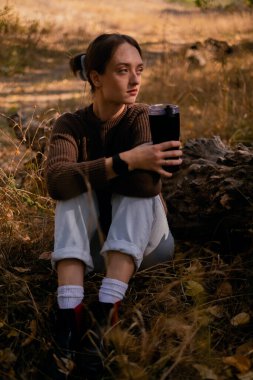 Genç bir kadın bir sonbahar günü dışarıda dinleniyor, ormana gidiyor, ormandaki ahşap bir kütükte oturuyor ve sıcak çay içiyor, doğayla bütünleşiyor, hayatın anlamını arıyor.