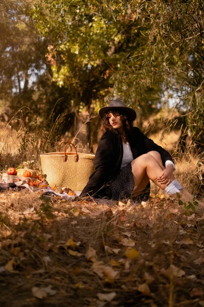 Autumn picnic outdoors, perfect autumn warm day, autumn picnic in nature, girl sitting on a blanket with a basket of groceries and a cup of hot tea, enjoying a sunny day, enjoying nature, solitude