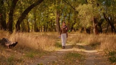 Parkta turist, sırt çantalı turist güneş ışığı altında orman parkında yürüyor, seyahat turizmi kavramları, ormanda turist yürüyüşü, kadın feminizmi kavramı