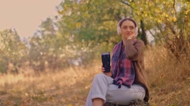 Sırt çantalı bir kadın, kahverengi bir kazak giymiş, elinde bir harita tutan, sonbahar ormanlarında güneşli havanın tadını çıkaran, uçurumun kenarında seyahat eden, 