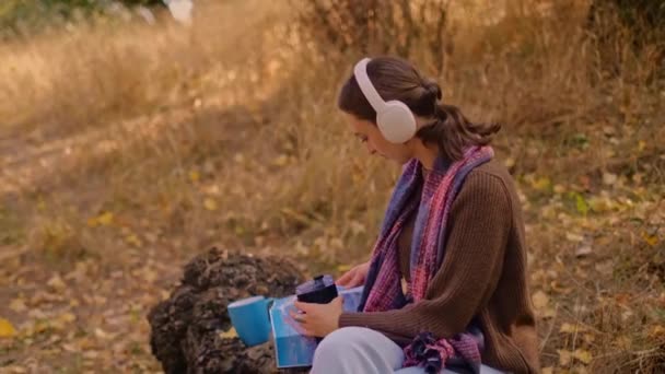 戴耳机的女人在公园里听音乐 在森林里欣赏音乐 年轻的高加索女人徒步旅行 森林里背着旅游背包的女孩 我的真正假期 我的真实假期 — 图库视频影像