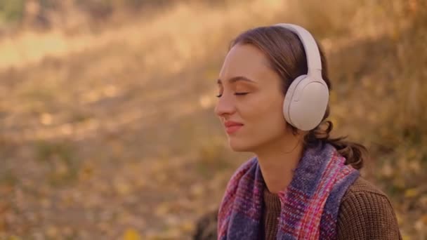 戴耳机的女人在公园里听音乐 在森林里欣赏音乐 年轻的高加索女人徒步旅行 森林里背着旅游背包的女孩 我的真正假期 我的真实假期 — 图库视频影像