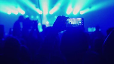 Adamın elleri video kayıtlarını cep telefonuyla kaydediyor. Bir grup hayran canlı bir K-Pop konserini kaydediyor. Birçok erkek çılgın festivallere gider. Eğlence grubu, gece kulübü salonu. Yıldız DJ elini kaldırıyor..